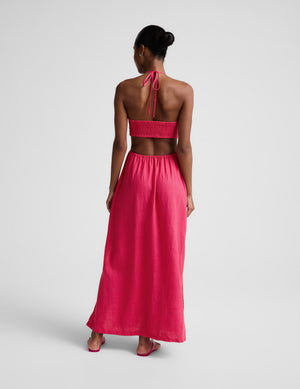 Woman wearing a red linen halter maxi dress against a plain background. 