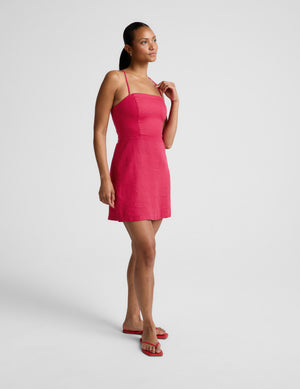 Woman wearing a red linen mini dress against a plain background. 
