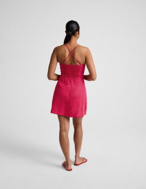 Woman wearing a red linen mini dress against a plain background. 