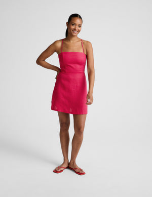 Woman wearing a red linen mini dress against a plain background. 
