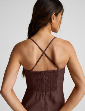 Woman wearing a brown mini linen dress against a plain background. 