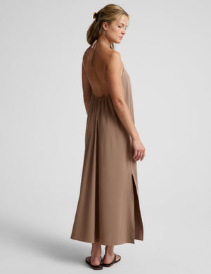 Woman wearing a brown halter maxi dress against a plain background. 