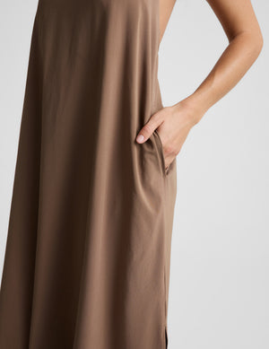 Woman wearing a brown halter maxi dress against a plain background. 