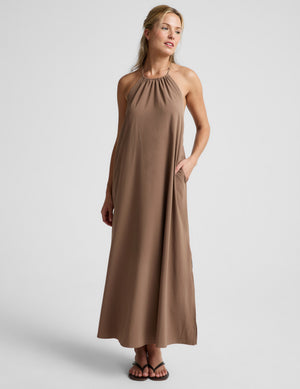 Woman wearing a brown halter maxi dress against a plain background. 
