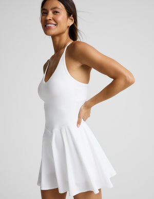 Woman wearing a white athletic mini dress with built-in shorts against a plain background. 
