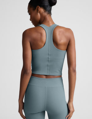 Woman wearing a blue ribbed cropped tank and shorts. 