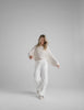 Woman wearing a white knit cropped sweater and fleece pants. 