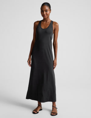 Woman wearing a black sleeveless racerback maxi dress on a light gray background. 