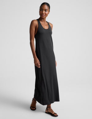 Woman wearing a black sleeveless racerback maxi dress on a light gray background. 
