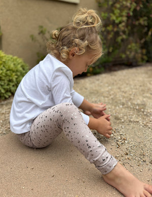Toddler playing in sand wearing the beige Chai Mini Moons SoftShine Toddler Legging with shimmering moon prints.