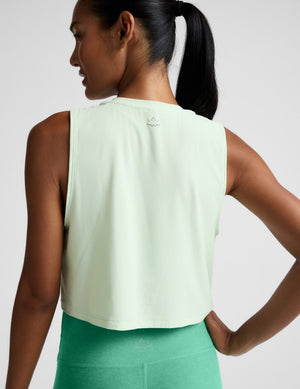 Woman wearing a light green sleeveless top and leggings against a plain background. 