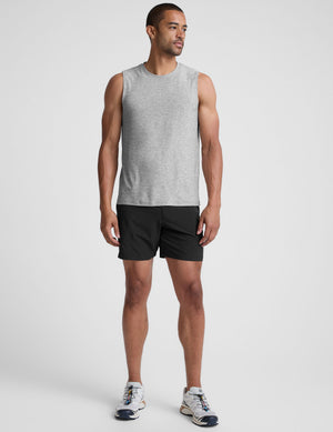 man wearing a gray sleeveless shirt against a plain background. 