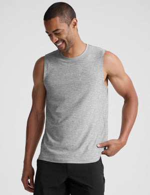 man wearing a gray sleeveless shirt against a plain background. 
