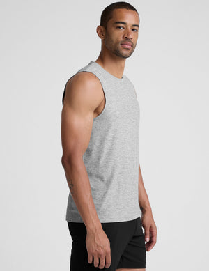 man wearing a gray sleeveless shirt against a plain background. 