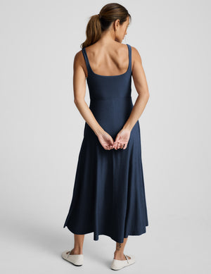 Woman wearing a blue sleeveless dress on a white background. 
