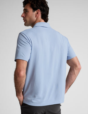 Man wearing a light blue polo shirt against a plain background. 