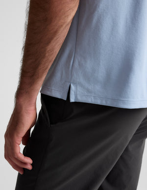 Man wearing a light blue polo shirt against a plain background. 