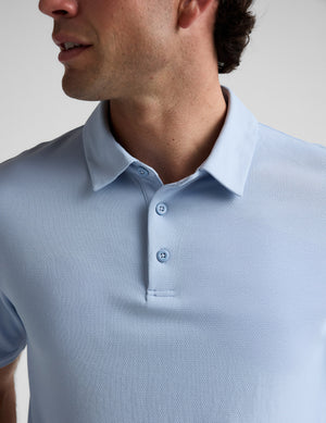 Man wearing a light blue polo shirt against a plain background. 