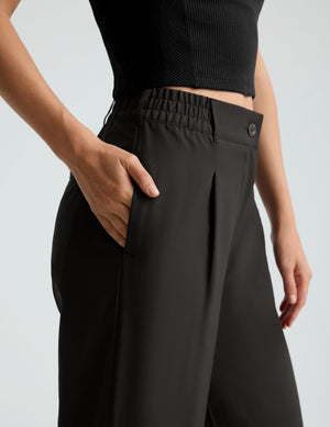 Close-up of the black Status Wide Leg Trouser showing side pockets, pleated front, and elastic waistband on a model.