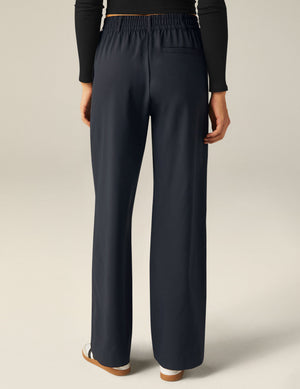 Rear view of a person wearing black Status Wide Leg Trousers with an elastic waistband, belt loops, and a back welt pocket.