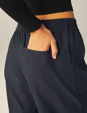 Hand in the back welt pocket of black Status Wide Leg Trousers, showing the elasticated waistband and belt loops.