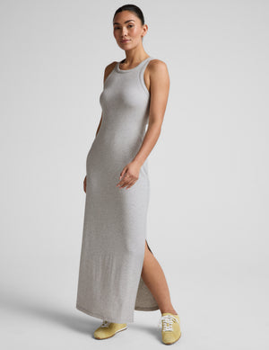 Woman wearing a gray high neck ribbed maxi dress against a plain background. 