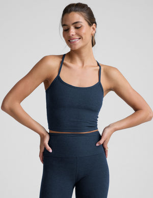 woman wearing a navy blue racerback cropped tank and leggings on a plain background. 