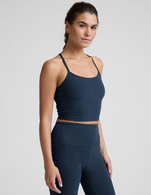 woman wearing a navy blue racerback cropped tank and leggings on a plain background. 